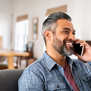 Man smiling while talking on phone at home
