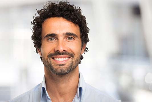 Man with curly hair in collared shirt smiling