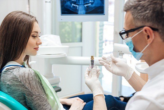 Dentist showing patient dental implant  model