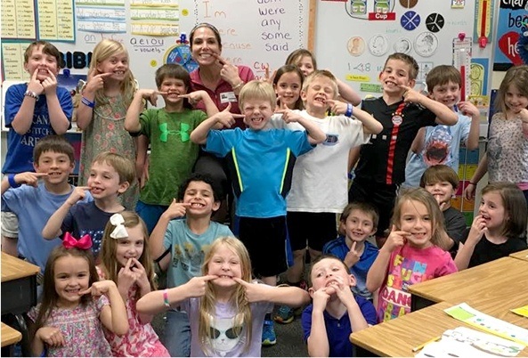 Classroom of children in Raleigh pointing to their smiles