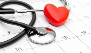 Red heart and stethoscope on white calendar 