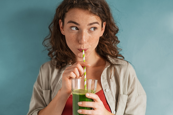 woman drinking green drink out of straw