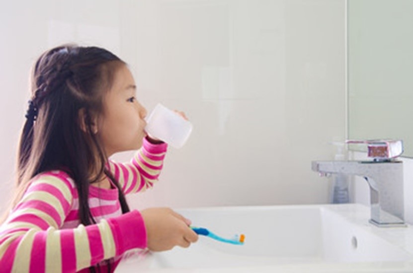 Little girl rinsing her mouth as part of her dental hygiene