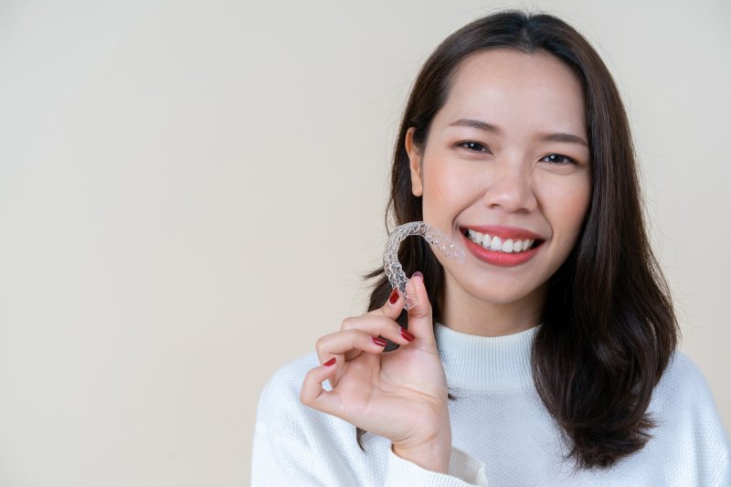 person holding Invisalign and smiling