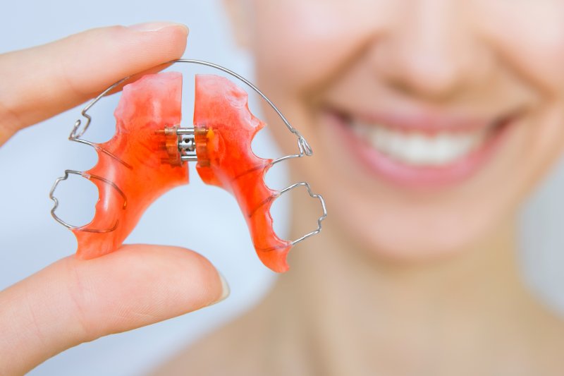 A patient holing a retainer to use after Invisalign in Raleigh