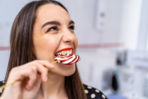 a person biting directly into a lollipop